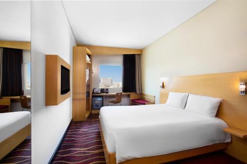 马斯喀特ibis Muscat的酒店客房设有一张白色大床和一张书桌