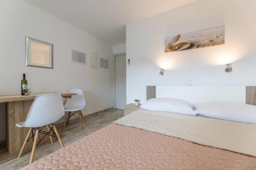 巴斯卡Apartments Augustinovic的一间卧室配有一张床和一张带两把椅子的桌子