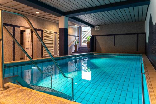 奥巴拉马高松嫩霍夫公园酒店的一座位于大楼内的蓝色瓷砖室内游泳池