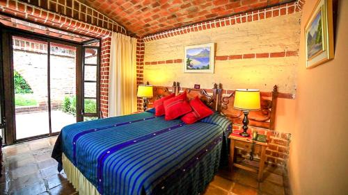 帕纳哈切尔Hotel San Buenaventura de Atitlán的一间卧室配有蓝色和红色枕头的床