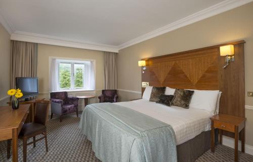 拉夫堡Quorn Country Hotel Leicester的酒店客房设有一张大床和一张书桌。