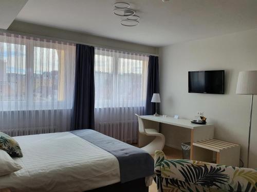 拉绍德封Athmos Résidence - Hotel的酒店客房设有一张床、一张书桌和窗户。