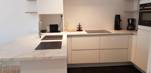 克诺克－海斯特Nieuwbouwappartement Lippenslaan met 2 slaapkamers - WIFI - 6 personen的厨房配有白色橱柜和台面