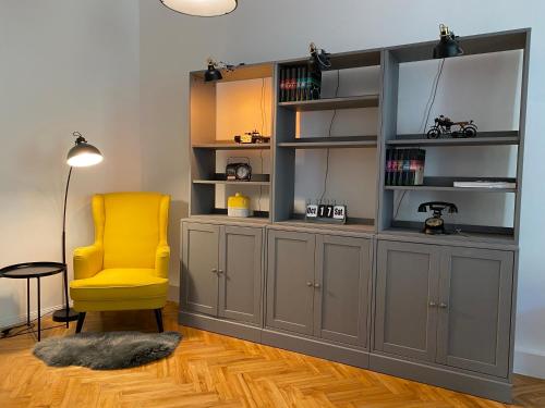 林茨Industrial Apartment Schlossberg的书架和黄色椅子的房间