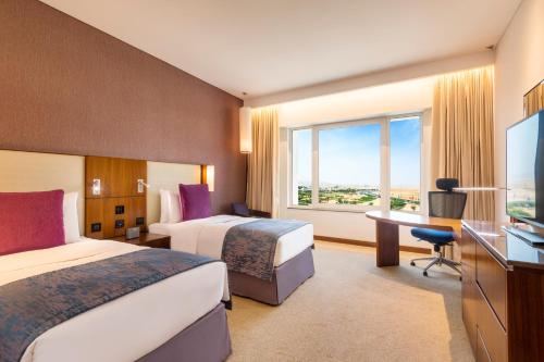 马斯喀特马斯喀特OCEC皇冠假日酒店的酒店客房设有两张床、一张书桌和一个窗户。