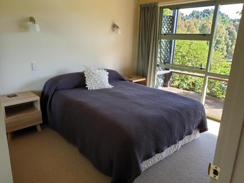 奥玛鲁Fairway Cottage的一间卧室设有一张床和一个大窗户