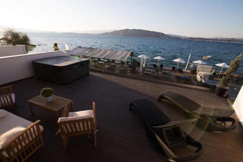 AiándionAianteion Bay Luxury Hotel & Suites的阳台配有桌椅,享有水景。