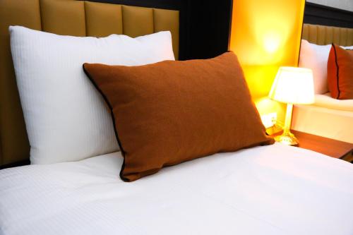 伯萨Dimen Hotel的床上有棕色枕头