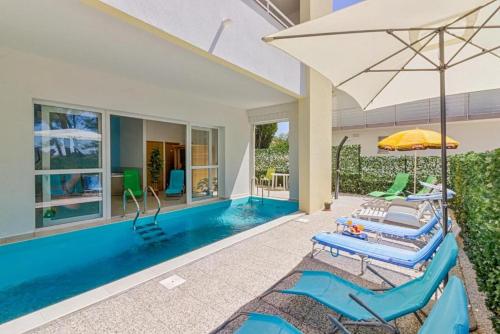 扎达尔Apartments Villa Ema的一个带2把躺椅和遮阳伞的游泳池