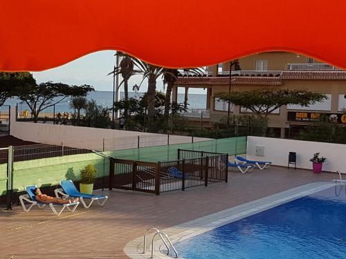 洛斯克里斯蒂亚诺斯PLAYA LAS VISTAS LOFT的享有带椅子的游泳池和大楼的景色