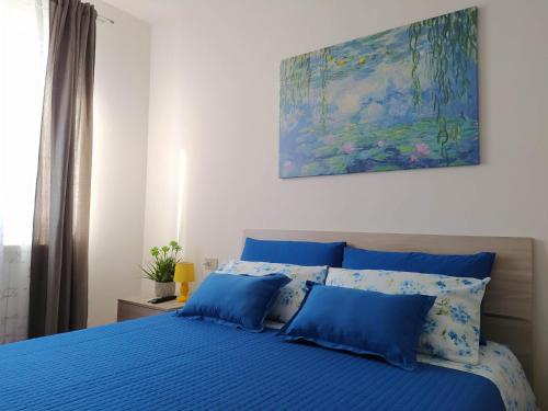 TreglioLa Casa al Colle的一张蓝色的床,上面有蓝色枕头和墙上的画作
