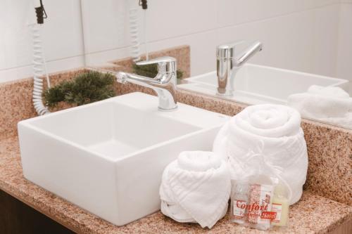 圣安娜-利弗拉门图Confort Fronteira Hotel的浴室水槽和台面上的毛巾
