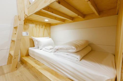 首尔明洞1号步伐旅舍的客房内的双层床配有白色床单和枕头