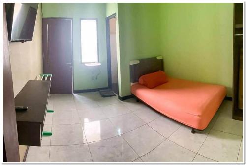 沙马林达KoolKost Syariah near Gedung DPRD Prov. KalTim的绿色的客房设有窗户,配有橙色的床。