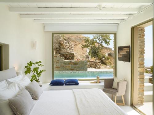 提诺斯埃俄利斯蒂诺斯套房度假屋的一间卧室配有一张床,享有游泳池的景色