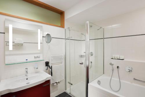 Vendryně活力酒店的一间带玻璃淋浴、水槽和浴缸的浴室