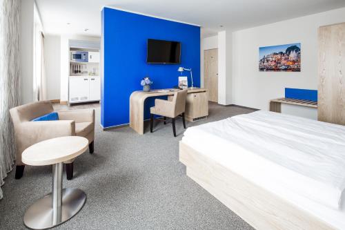 沃尔夫斯堡全球酒店的一间设有蓝色墙壁、一张床和一张书桌的卧室