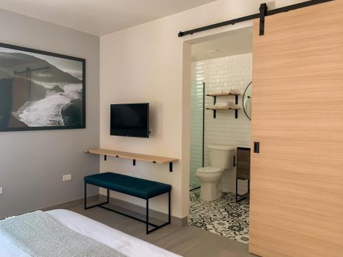 圣胡安The Ivy Hotel的一间带床和卫生间的浴室以及一台电视。
