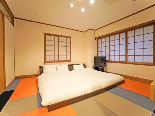 高松高松市一区酒店的卧室设有一张白色大床和两个窗户。
