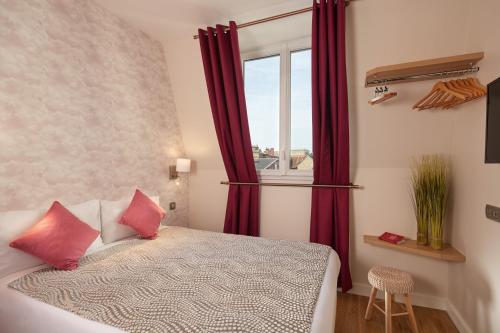 布洛涅-比扬古Hôtel Villa Sorel - Paris Boulogne的一间卧室配有一张带红色窗帘的床和一扇窗户