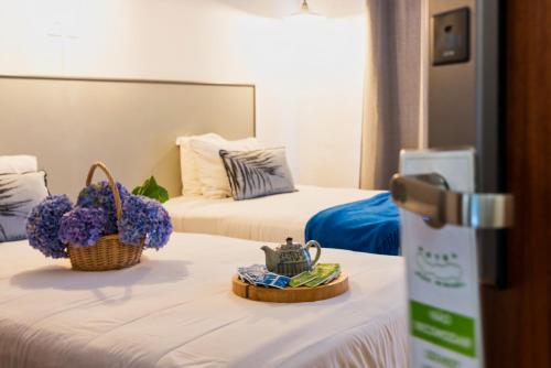 蓬塔德尔加达Hotel São Miguel的配有两张带鲜花的桌子的床的酒店客房