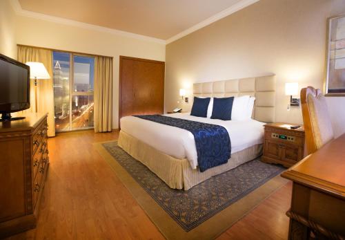迪拜Millennium Plaza Downtown Suites的酒店客房设有一张大床和一台电视。