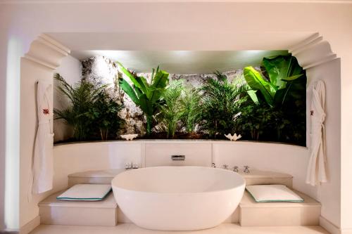 波西塔诺圣彼得波西塔诺酒店的带浴缸和墙上植物的浴室。