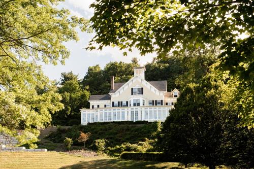 伊萨卡Inn at Taughannock Falls的一座树木茂密的山丘上的白色大房子