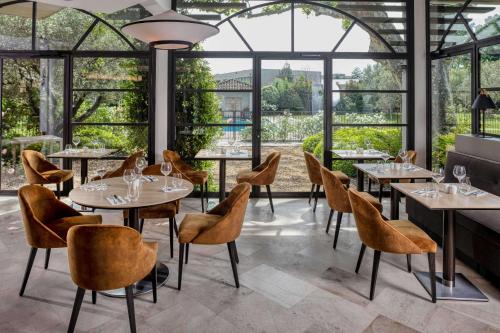 阿维尼翁拉瓦林贝斯特韦斯特优质酒店的餐厅设有桌椅和大窗户。