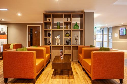 英格里斯顿爱丁堡机场智选假日酒店 的一间备有橙色椅子和桌子的等候室