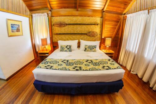 科科波科可波海滩别墅度假村的卧室配有一张床铺,位于带木墙的房间内