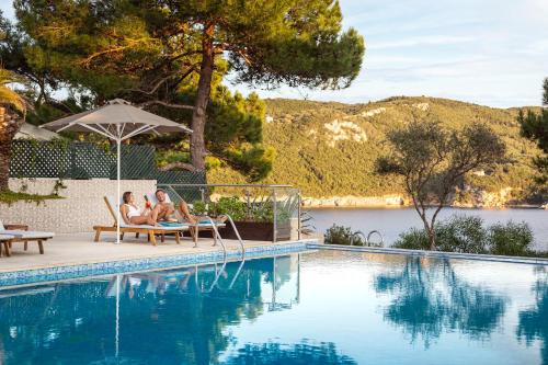 帕莱欧卡斯提撒Akrotiri Beach Resort Hotel - Adult Friendly的两人坐在游泳池旁的椅子上