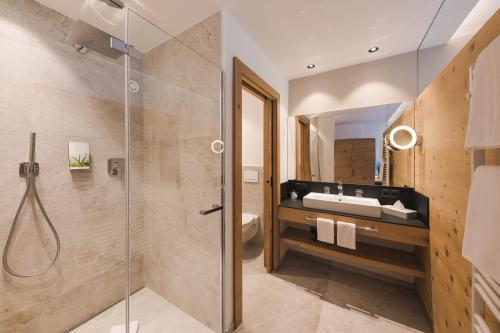 思科纳Naturhotel Gruberhof的一间带玻璃淋浴和水槽的浴室