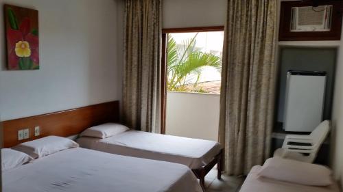 普拉杜Quiriri Park Hotel的酒店客房设有两张床和窗户。