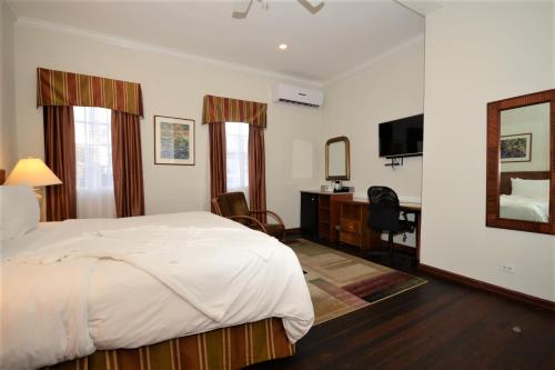 乔治敦卡拉洛奇酒店的一间卧室配有一张床、一张书桌和一面镜子