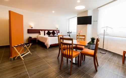 普埃布拉Mision Puebla Angelopolis的酒店客房带一张床、一张桌子和椅子