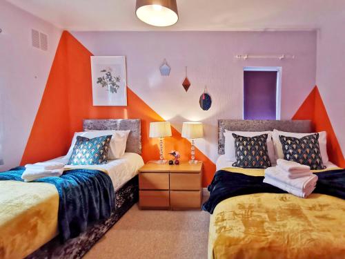 巴恩斯利Noknokstay-Highstone House,4 Bedrooms, Garden with Parking, Great for Longer Stay的一间卧室设有两张床和橙色的墙壁