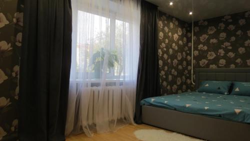 波洛茨克Апартаменты Art House в центре Полоцка的一间卧室配有床和带窗帘的窗户