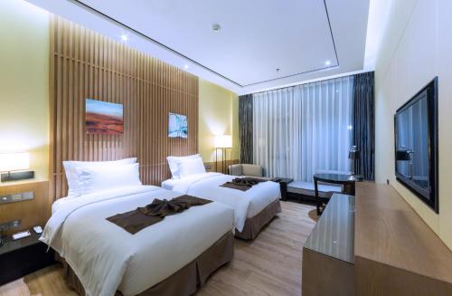 珠海珠海棕泉水疗酒店的酒店客房设有两张床和一台平面电视。