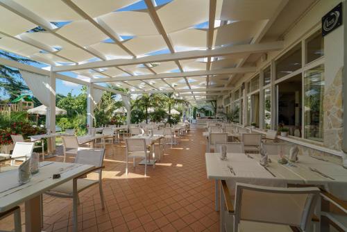 梵蒂冈角卡拉布里亚拉布索拉酒店的餐厅设有白色的桌椅和窗户。