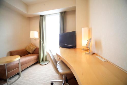 仙台里士满酒店普利米尔仙台站前的客房设有一张桌子、一张沙发和一台电视机
