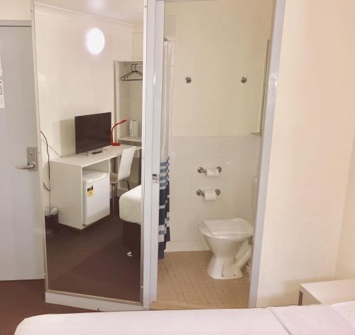 布里斯班Turbot House Hotel的一间带卫生间的浴室和一张书桌及一台电视
