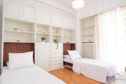 雅典Spacious and Luxurious Apartment in Athens Center的配有白色橱柜和窗户的客房内的两张床
