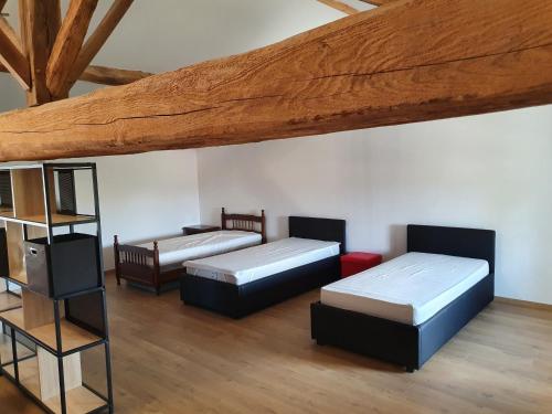 MarlieuxGîte Le Bonnet的客房设有三张床和木制天花板。