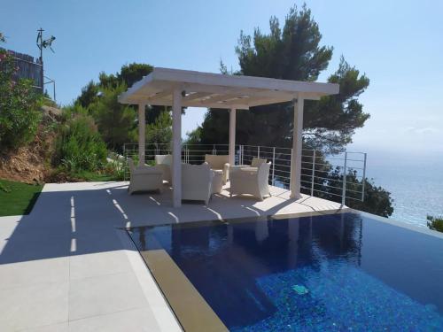 雅莎尼奥Okeanos Luxury Villas - Resort的毗邻大海的带凉亭的游泳池
