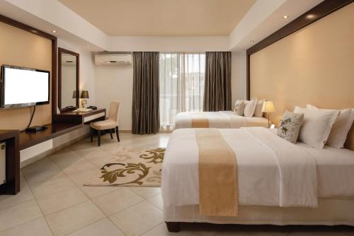 达累斯萨拉姆Peninsula Hotel Dar Es Salaam的酒店客房设有两张床和一台平面电视。