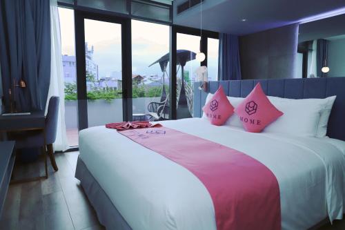 胡志明市HOME Hotel的卧室配有一张带粉红色枕头的大床