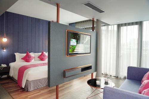 胡志明市HOME Hotel的一间卧室配有一张带粉色枕头的床和一台电视。
