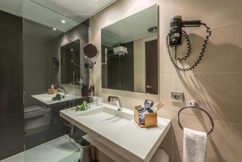 奥洛特Hotel Olot Centre的一间带水槽、镜子和淋浴的浴室