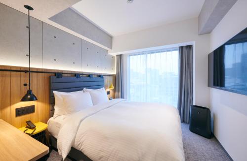 名古屋ibis Styles Nagoya的卧室设有一张白色大床和一扇窗户。